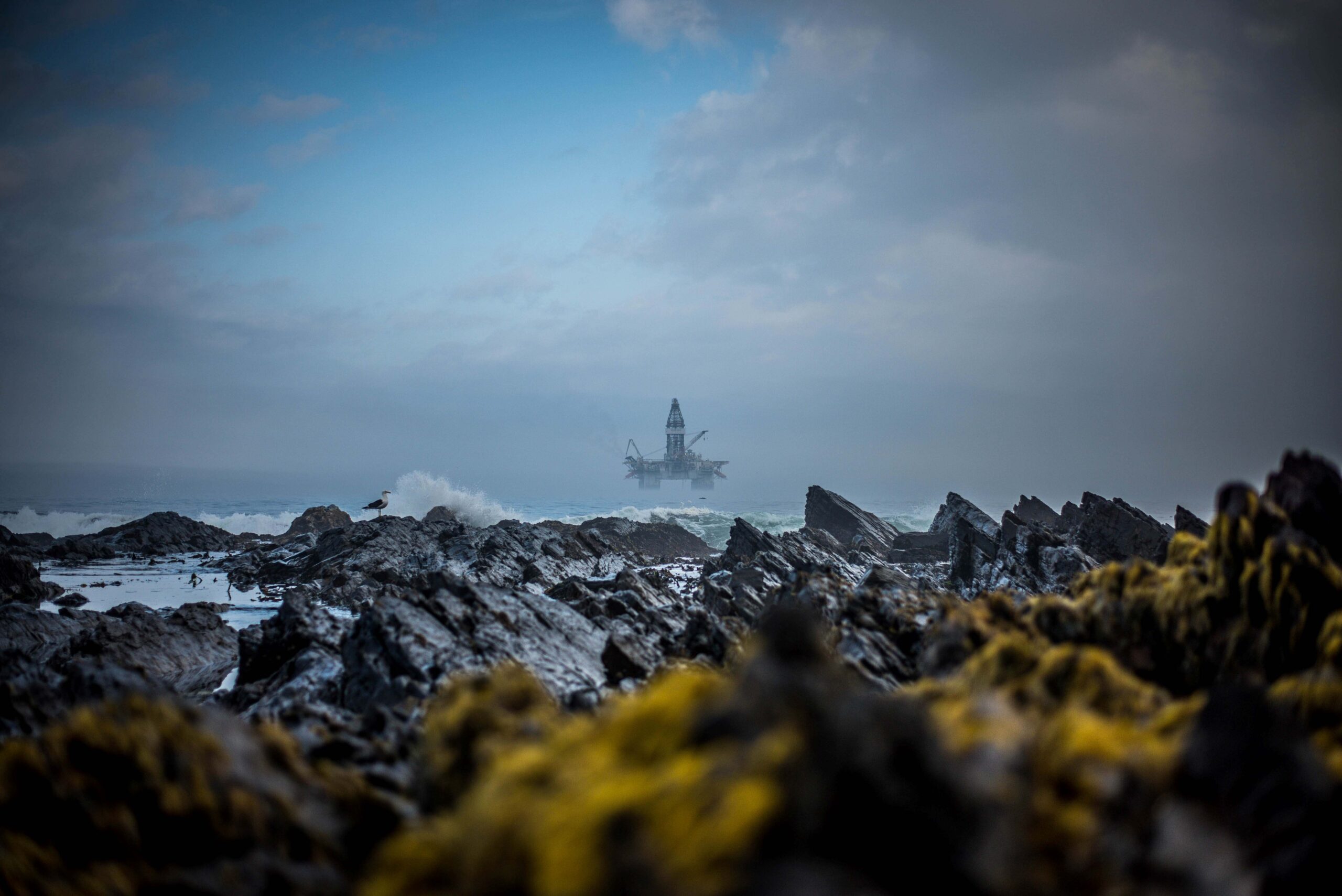 Oil platform in the background with rocky shore in front