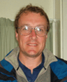 A man with short hair and glasses smiles at the camera