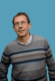 Man smiling into the camera, wearing short hair and glasses